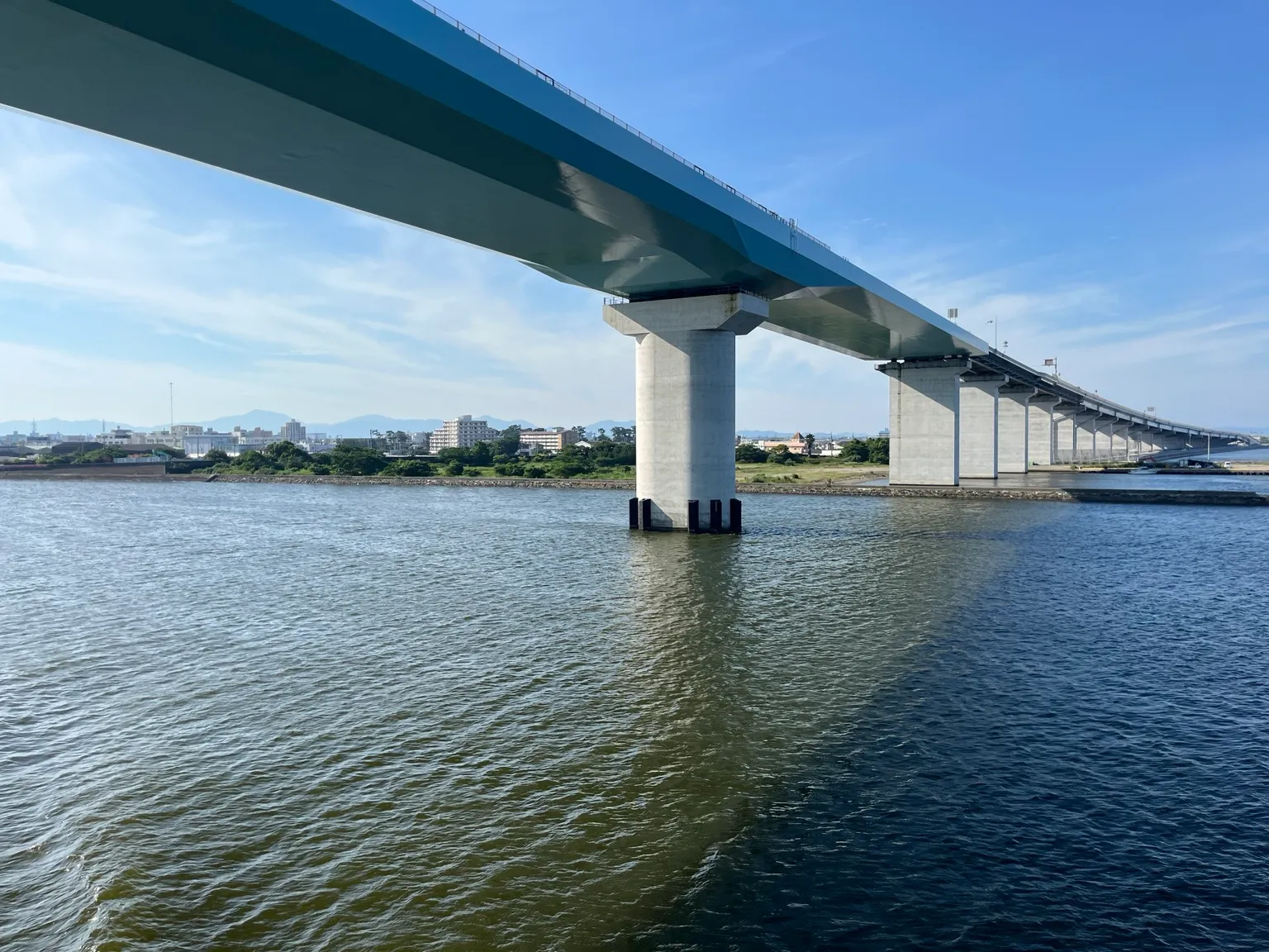 南海フェリーの甲板から見上げた海上の橋と遠くの街並み