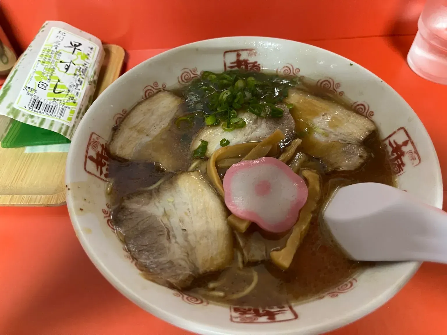 花柄のかまぼこやチャーシューが乗った井出商店の中華そばと、パッケージに入った早すし